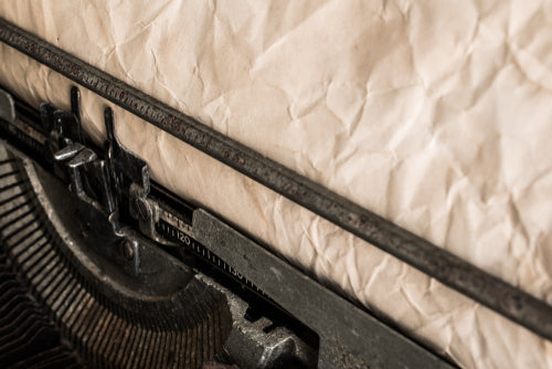 Vintage typewriter loaded with a sheet of crumpled, weathered paper.